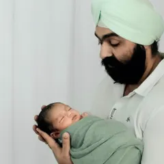 A father gazes lovingly at his swaddled newborn. These quiet, tender moments between a parent and child are the foundation of a family's story.