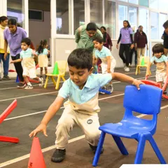 An obstacle course on Sports Day challenges children to navigate cones and chairs, building agility and problem-solving skills.