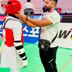 A coach's role is to prepare the student mentally and physically. Here I am making final adjustments to a student's protective headgear before their Kyorugi match at the World Expo.