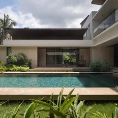 The pool court at Villa Shakthi is designed as the heart of the home. This view from the garden shows how the living spaces open directly onto the pool deck, blurring the lines between inside and out in a way that is ideal for tropical settings.