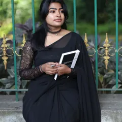 A full-shot from a professional photoshoot in a classic black saree. The makeup is clean and defined, with a focus on sharp brows and a neutral lip to suit the elegant theme.