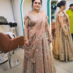 A full-length photo of a client looking elegant for a party in a peach-colored lehenga. The makeup is soft and sophisticated, perfect for a mature client.