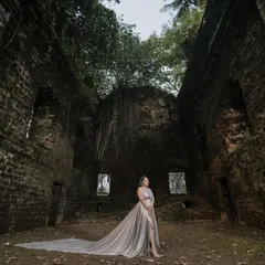 A stunning shot featuring our silver trail gown. The metallic fabric and long trail create a beautiful contrast against the historic, rustic location, perfect for a pre-wedding shoot.