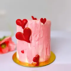 A close-up of one of my Valentine's Day mini cakes. This one has a beautiful pink and white textured buttercream finish and is adorned with delicate red hearts.