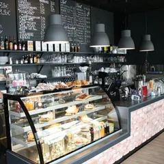 A well-designed service counter is crucial for any cafe. Here, we designed a functional counter area with a brick facade, a curved glass display for pastries, and a dark, moody color scheme that contrasts with the warm lighting, ensuring an efficient workflow and an attractive point of sale.