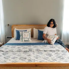 Our co-founder Abhinayah adding the final touches to this beautiful blue-themed bedroom. The space features our floral quilt, matching bed runner, and a curated selection of our custom cushion covers for a complete, harmonious look.