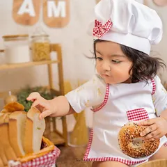 A bagel and a slice of bread, the perfect snack for a busy little baker. The details in this chef-themed setup create a rich, story-telling image.