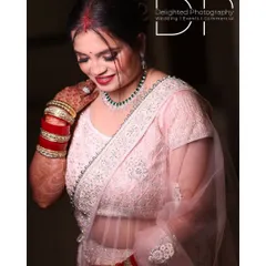 A beautiful portrait of a bride at her reception, showcasing her elegant light pink saree, traditional red and white bangles, and happy smile.