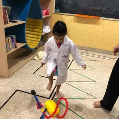 Preparing for takeoff! A child in a lab coat gets ready to launch a toy rocket, learning about basic principles of physics and force.