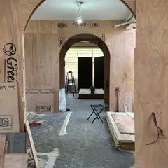 A side-by-side look at the power of transformation. What was once a bare construction site with raw plywood arches became a warm, inviting passage, where fabric-wrapped structures and soft lighting guide you through the store's unfolding story.