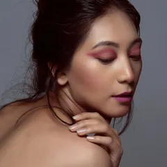 This profile shot highlights the vibrant pink eyeshadow and clean skin finish. The focus is entirely on the artistic makeup, showing how color can be used to create a powerful beauty statement.