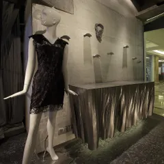 A detail of the Gaurav Gupta store interior, showing a custom-fabricated metal console with a draped texture against a raw concrete wall. This juxtaposition of refined metalwork and rough material is a recurring theme in the project.