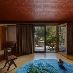 The living room in the Madhura house opens directly to the garden, centered around the Tulasi Brindavan. The combination of a yellow Jaisalmer stone floor and a terracotta vault roof fills the space with warmth.