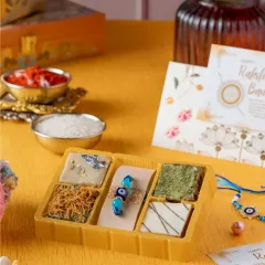 This limited-edition brownie box is perfect for Rakshabandhan. It features unique fusion flavors like Matcha, Kaju Katli, and Kunafa brownies, and comes paired with an Evil Eye Rakhi.