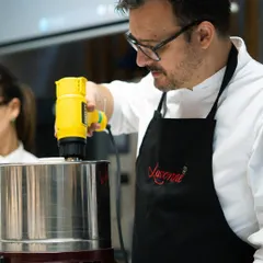 Chef Olivier Fernandez from EPGB Barcelona leads a bean-to-bar chocolate masterclass. Here he is using a melanger to grind cacao nibs, a key step in the chocolate-making process.