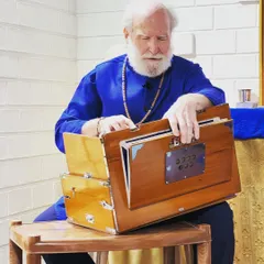 A close-up of Nayaswami Haridas, deeply absorbed in playing the harmonium. Chanting is a form of yoga that directs the heart's energy toward God.