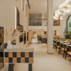 The interior is bright and airy, with a double-height ceiling, a neutral palette, and a striking checkered console table that adds a touch of modern geometry.