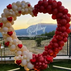 This outdoor heart-shaped balloon arch is perfect for a romantic birthday or anniversary. The red and white balloons and a 'Happy Birthday' neon sign create a stunning photo opportunity, especially at sunset.