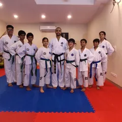 A group of our students who have just been promoted, standing together with their coach. Each new belt represents a milestone achieved.