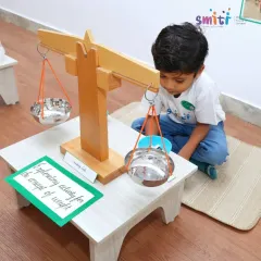 A child demonstrates the concept of weight using a balancing scale, an activity from our "Coconut Chronicles" project. This shows parents how we make scientific concepts tangible.