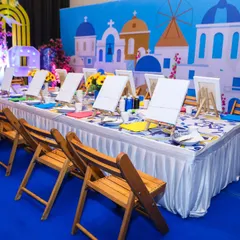 A beautiful canvas painting station set up for a Greece-themed party, with individual easels and a stunning Santorini backdrop.