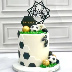 A goal-worthy cake for a young football fan. This design features a hexagonal football pattern, edible soccer balls, and a personalized "Happy Birthday" topper, making it the perfect treat for a sports-themed party.