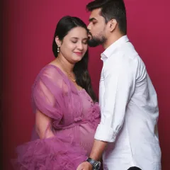 A tender moment between partners during a studio maternity session. The father-to-be gently kisses his partner's forehead, creating a feeling of love and protection.