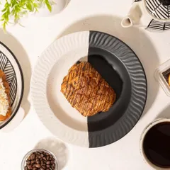 A before-and-after style shot for Homesmith, showing a modern black-and-white plate first empty, then with a croissant. This interactive concept is engaging for social media and shows the crockery's use.