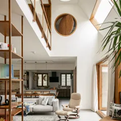 This view from the living room shows how the double-height space connects different levels of the home. The large indoor plants and abundant light from the skylights make the entire area feel like a single, open garden.