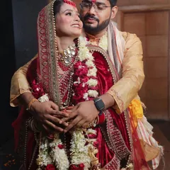 This photo captures the happy and relaxed connection between the newlyweds. The groom embraces the bride from behind as she looks up at him with a radiant smile. It’s a warm, candid moment that showcases their joy right after the ceremony.