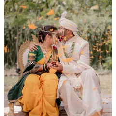 A beautiful moment of a Maharashtrian couple seated after their wedding rituals, with flower petals showered upon them in celebration.