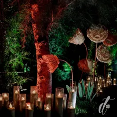 We love to integrate artistic, sculptural elements. These oversized, hand-woven flowers, illuminated by surrounding candles, added a touch of modern craft to the rustic, natural setting of the event entrance.