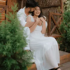 A moment of pure, uninhibited laughter on a rustic wooden porch. Dressed in coordinated white, this couple's joy is infectious, showcasing a perfectly candid moment from their pre-wedding shoot.