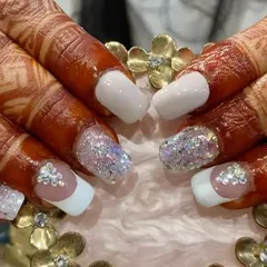 A beautiful bridal look on henna-adorned hands, featuring white tips, chunky iridescent glitter, and delicate crystal accents.