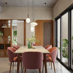 This dining area uses a warm, earthy color palette with dusty rose chairs and a wooden table. The space is lit by a cluster of modern pendant lights and opens onto a patio through large sliding doors.