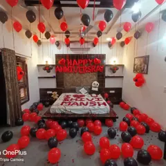 A personalized anniversary room setup in red and black. I used rose petals to write the couple's names on the bed and filled the room with balloons for a dramatic and personal touch.