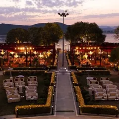 An aerial view of a stunning lakeside venue in Udaipur at sunset. Udaipur is one of the world's top wedding destinations, and we specialize in transforming its regal venues into magical settings.