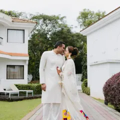 An intimate portrait of a couple in matching white outfits, about to share a kiss in a beautiful garden path, showcasing a quiet moment of love.