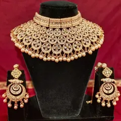 A classic gold-plated Polki choker set with matching chandbali earrings. The pearl drops add a touch of elegance to this timeless design.
