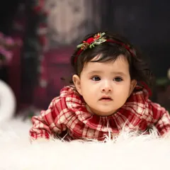 A thoughtful gaze from a sweet baby girl. Dressed in a festive plaid top, her curious expression is the focus of this simple and beautiful portrait.