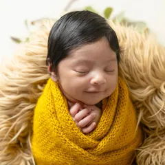 A peaceful newborn wrapped snugly in a yellow knit blanket, dreaming sweetly. I use soft textures and warm colors to create cozy and artistic newborn portraits.