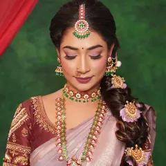 A close-up of this elegant Muhurtham look. Notice the soft pink and mauve tones on the eyes, which perfectly match the intricate jewelry and saree. The look is finished with a beautiful messy braid adorned with fresh flowers.