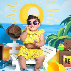 A sunny beach theme for a happy baby girl. Even indoors, we can create a fun summer vibe with a painted backdrop, beach chair, and playful props.