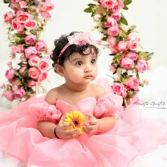A princess on her floral swing. Surrounded by pink roses and sitting on a bed of clouds, this is a true fairytale moment captured forever.