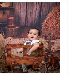 A beautiful, happy portrait of the baby boy in the vintage cart setup. His bright smile and the warm, rustic tones of the photo create a memory that will be cherished for years.