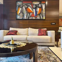 Jagannath Paul's abstract figurative work creates a dynamic focal point against a dark wood-paneled wall, adding a layer of contemporary sophistication to the living space.