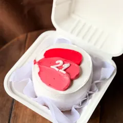 A pretty and minimalist bento cake with pink and red abstract brushstrokes. The number "22" is piped in the center, making it a chic and modern birthday cake.