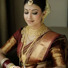A portrait of timeless Bengali bridal beauty. The combination of the red and gold saree, the traditional jewelry, and the iconic eye makeup with chandan dots is simply magical.