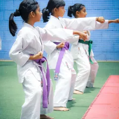 Three young girls demonstrate a synchronized punching technique, showing the precision and unity we foster in our group training sessions for belt examinations.