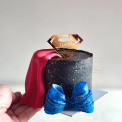A handheld view of the Superman-themed bento cake. You can see the details of the fondant cape and bow tie, making it a fun and memorable cake for any dad.